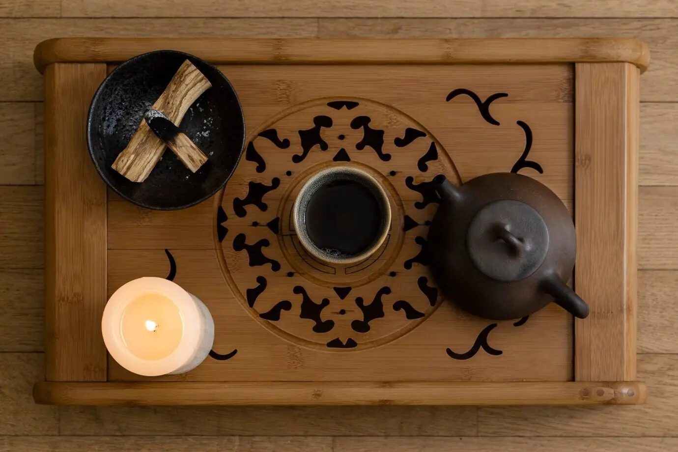 Blick von oben auf Teetasse, Teekessel und brennende Kerze.