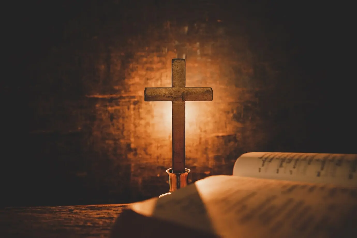 Aufgeschlagene Heilige Bibel und eine Kerze auf einem alten Tisch aus Eichenholz. Schöner goldener Hintergrund. Konzept: Religion.